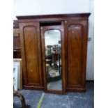 A MAHOGANY COMPACTUM WARDROBE, THE CENTRAL MIRRORED DOOR FLANKED BY PANELLED DOORS OVER HANGING