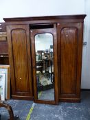 A MAHOGANY COMPACTUM WARDROBE, THE CENTRAL MIRRORED DOOR FLANKED BY PANELLED DOORS OVER HANGING