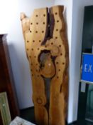 A TREE TRUNK PANEL PIERCED AS A BOTTLE RACK. W 94 x H 244cms.