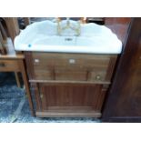 A CERAMIC WASH BASIN WITH GILT MIXER TAPS, THE PINE BASE WITH DRAWERS AND A DOOR BETWEEN FLUTED