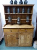 A PINE DRESSER WITH ENCLOSED TWO SHELF BACK, THE BASE WITH TWO DRAWERS AND DOORS. W 125 x D 55 x H