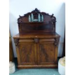 A VICTORIAN MAHOGANY TWO DOOR SIDE CABINET, THE FOLIATE CARVED BACK WITH SERPENTINE FRONTED SHELF. W