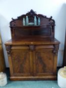 A VICTORIAN MAHOGANY TWO DOOR SIDE CABINET, THE FOLIATE CARVED BACK WITH SERPENTINE FRONTED SHELF. W