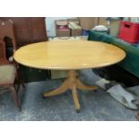 AN OAK OVAL TOPPED TABLE ON BALUSTER COLUMN AND FOUR LEGS WITH MODERN CASTOR FEET