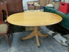 AN OAK OVAL TOPPED TABLE ON BALUSTER COLUMN AND FOUR LEGS WITH MODERN CASTOR FEET