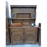 AN OAK DRESSER WITH A SHELF CENTRAL TO THE ENCLOSED BACK FLANKED BY LEADED GLASS DOORED PIGEON
