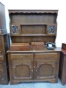 AN OAK DRESSER WITH A SHELF CENTRAL TO THE ENCLOSED BACK FLANKED BY LEADED GLASS DOORED PIGEON