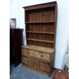A PINE DRESSER, THE ENCLOSED SHELF BACK ABOVE TWO DRAWERS AND TWO PLANK BUILT DOORS