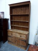 A PINE DRESSER, THE ENCLOSED SHELF BACK ABOVE TWO DRAWERS AND TWO PLANK BUILT DOORS