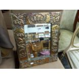 A BEVELLED GLASS RECTANGULAR MIRROR IN ARTS AND CRAFTS COPPER FRAME MODELLED WITH GROUPS OF THREE