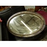 AN OVAL BEVELLED GLASS MIRROR IN SILVER PLATED FRAME