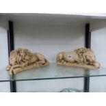 A PAIR OF CAST CERAMIC RECLINING LIONS