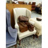 A CREAM UPHOLSTERED WING ARMCHAIR ON MAHOGANY CABRIOLE FRONT LEGS WITH PAD FEET