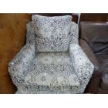AN ARMCHAIR UPHOLSTERED IN GREYS WITH WHITE CUT WORK VELVET PATTERNS