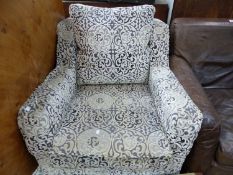 AN ARMCHAIR UPHOLSTERED IN GREYS WITH WHITE CUT WORK VELVET PATTERNS