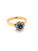 AN 18ct YELLOW GOLD HALLMARKED SAPPHIRE AND DIAMOND CLUSTER RING. THE CENTRAL SAPPHIRE APPROX 4mm