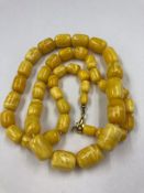 A GRADUATED ROW OF KNOTTED CYLINDRICAL AMBER BEADS. APPROX LENGTH 77cms. BEADS APPROX 7.3 TO 14.