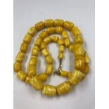 A GRADUATED ROW OF KNOTTED CYLINDRICAL AMBER BEADS. APPROX LENGTH 77cms. BEADS APPROX 7.3 TO 14.