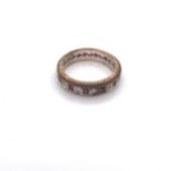 A 9ct YELLOW AND WHITE GOLD HALLMARKED SYNTHETIC SPINEL AND RUBY FULL ETERNITY RING. DATED 1986,