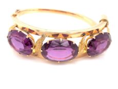 AN ANTIQUE 14ct YELLOW GOLD THREE STONE HINGED BANGLE. THE THREE PRINCIPLE OVAL CUT FACET