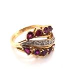 A RUBY AND DIAMOND DRESS RING. TEN PEAR CUT RUBIES FRAME A GRAIN SET WAVE OF DIAMONDS. APPROX RUBY