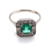 A VINTAGE ART DECO STYLE EMERALD AND DIAMOND HALO SET RING. THE CENTRAL EMERALD A MIXED CUT