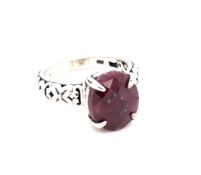 A RED CORUNDUM CARVED RING. THE OVAL FACET CUT RUBY IN A FOUR CLAW SETTING, WITH CARVED OPEN