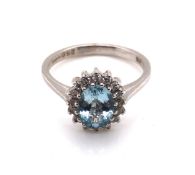 AN 18ct WHITE GOLD HALLMARKED AQUAMARINE AND DIAMOND SET CLUSTER RING. THE AQUAMARINE APPROX 9 x