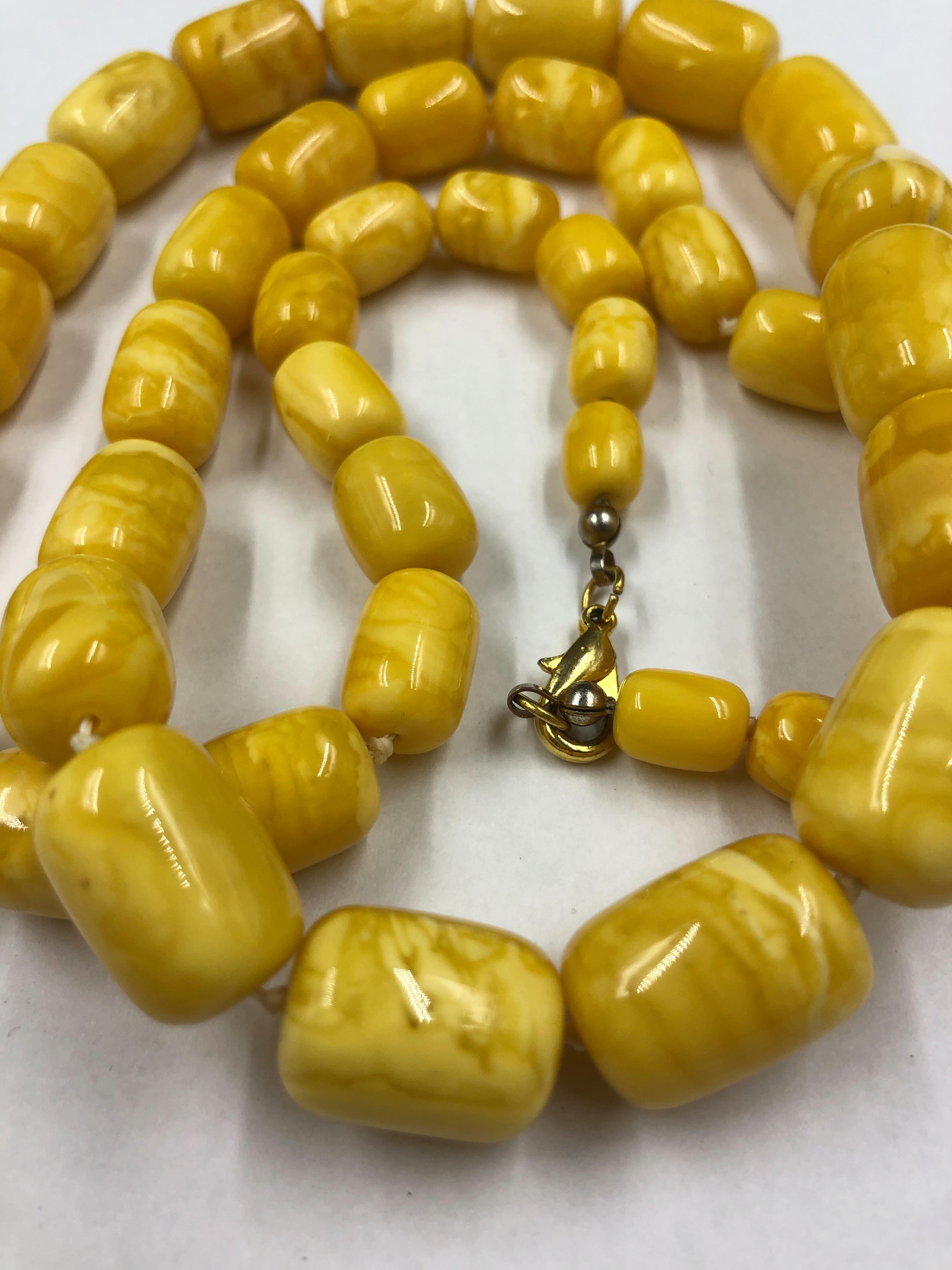 A GRADUATED ROW OF KNOTTED CYLINDRICAL AMBER BEADS. APPROX LENGTH 77cms. BEADS APPROX 7.3 TO 14. - Image 2 of 2