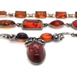 AN AMBER LAVALIER STYLE FOLIATE NECKLACE, TOGETHER WITH A FIVE PANEL AMBER SET NECKLACE AND A TEN