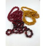 THREE ROWS OF UNTESTED BEADS CONSISTING OF TWO RED STRANDS AND ONE AMBER COLOURED STRAND. (THE AMBER