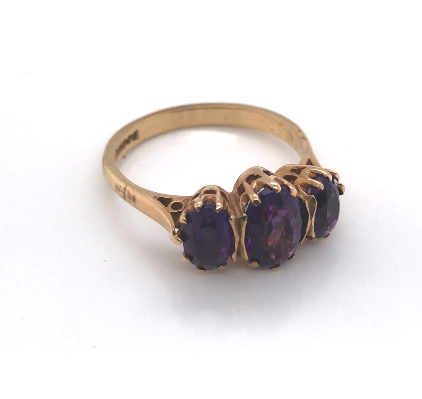 A 9ct YELLOW GOLD HALLMARKED THREE STONE GRADUATED AMETHYST RING. DATED 1974, BIRMINGHAM. FINGER