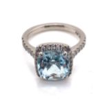 A CUSHION CUT AQUAMARINE AND DIAMOND HALO RING. THE SHANK STAMPED PLAT 950, AND ASSESSED AS