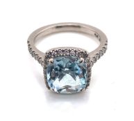 A CUSHION CUT AQUAMARINE AND DIAMOND HALO RING. THE SHANK STAMPED PLAT 950, AND ASSESSED AS