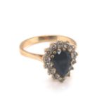 A 9ct HALLMARKED GOLD DARK BLUE SAPPHIRE PEAR CUT CLUSTER RING. THE SAPPHIRE SURROUNDED BY A CLUSTER