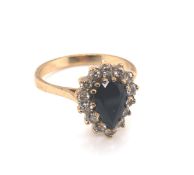 A 9ct HALLMARKED GOLD DARK BLUE SAPPHIRE PEAR CUT CLUSTER RING. THE SAPPHIRE SURROUNDED BY A CLUSTER