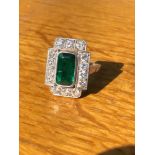 AN ART DECO EMERALD AND DIAMOND PANEL RING. THE LOZENGE SHAPE EMERALD APPROX 11 X 6mm, SURROUNDED BY
