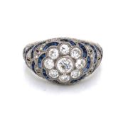 A SAPPHIRE AND DIAMOND BOMBAY RING. A CENTRAL DAISY CLUSTER WITH RADIATING SAPPHIRE AND DIAMOND