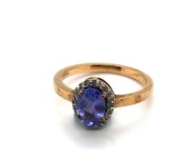 A TANZANITE AND DIAMOND HALLMARKED 9ct YELLOW GOLD CLUSTER RING. THE OVAL TANZANITE IN A FOUR CLAW