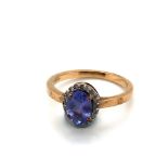 A TANZANITE AND DIAMOND HALLMARKED 9ct YELLOW GOLD CLUSTER RING. THE OVAL TANZANITE IN A FOUR CLAW