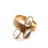 A VINTAGE 9ct YELLOW GOLD HALLMARKED THREE STONE MOONSTONE RING WITH BARKED FINISH BAND. DATED 1977,