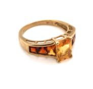 A 9ct YELLOW GOLD HALLMARKED OMBRE CITRINE DRESS RING. THE CENTRAL CITRINE IN A RAISED FOUR CLAW