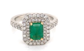 A PLATINUM AND 18ct YELLOW GOLD EMERALD AND DIAMOND DOUBLE HALO RING. THE CENTRAL EMERALD APPROX
