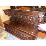 AN ANTIQUE CARVED OAK COFFER SEATED SETTLE. THE BACK AND FRONT CARVED WITH BIRDS AND SCROLLING FOLIA