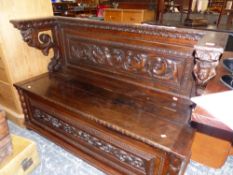 AN ANTIQUE CARVED OAK COFFER SEATED SETTLE. THE BACK AND FRONT CARVED WITH BIRDS AND SCROLLING FOLIA