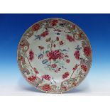 AN 18th C. CHINESE FAMILLE ROSE DISH PAINTED WITH FLOWERS WITHIN A SHAPED RED AMMONITE SCROLL RIM