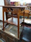 AN ART NOUVEAU MAHOGANY TWO TIER TABLE, THE PIERCED APRON BETWEEN SQUARE LEGS FLARING DOWN TO THE