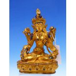 A TIBETAN GILT METAL FIGURE OF THE WHITE TARA SEATED ON A LOTUS THRONE, HER FACE AND HAIR WITH