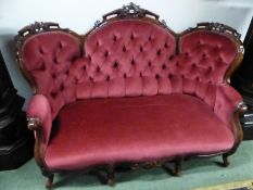 A VICTORIAN MAHOGANY BUTTON BACKED THREE SEAT SETTEE, THE TOP RAIL WITH THREE ROUND ARCHES CARVED