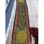 A MIDDLE EASTERN SILK BANNER WORKED IN GOLD THREAD WITH INSCRIPTIONS, THE CENTRAL BLACK PANEL
